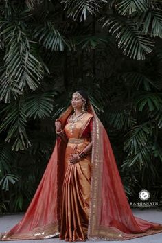 a woman in an orange and red sari with her hands on her hips, looking up