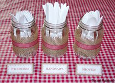 three mason jars with napkins in them on a red and white checkered tablecloth