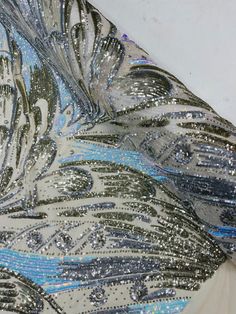 the back of a dress with silver and blue sequins on it's side