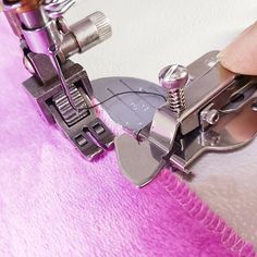 the sewing machine is being used to sew on pink furnishing fabric with scissors