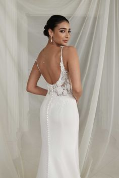 a woman in a white wedding dress with an open back and beading on it