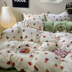 an unmade bed with strawberry print on the comforter and pillows, next to a round window