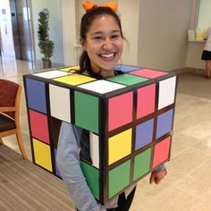 a girl is holding a rubik cube in her hands and smiling at the camera