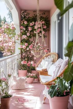 a porch with pink flowers on the wall and hanging chairs in front of it,