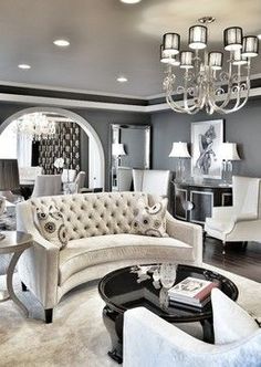 a living room filled with white furniture and lots of pillows on top of the couches