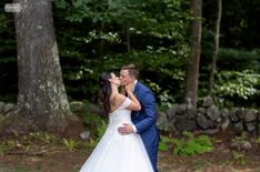 a bride and groom kissing in the woods