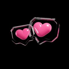 two pink heart shaped glasses sitting on top of a black surface with the reflection of them in