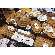 the table is covered with plates, cups and saucers on black plastic trays