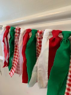 several different colored ties hanging from a line on a door hanger with white and red gingham checkered fabric