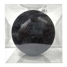 an ornament in a clear box with black and white speckles