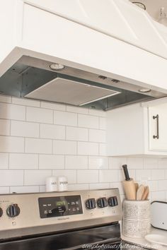 a stove top oven sitting inside of a kitchen next to a counter with utensils on it