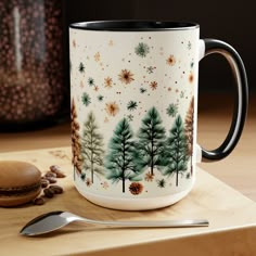 a coffee mug sitting on top of a wooden table next to a spoon and cup