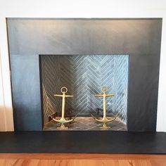 an empty fireplace with two gold anchors on it