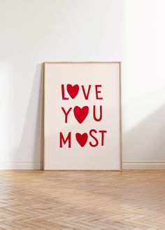 a framed love you most print sitting on the floor in front of a white wall