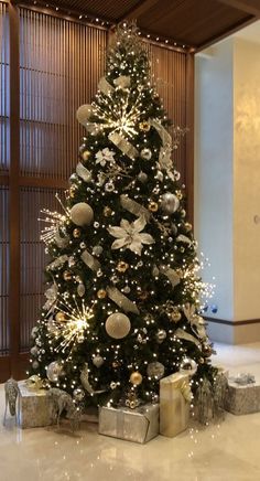 a christmas tree with presents under it and lights on the top, in a lobby