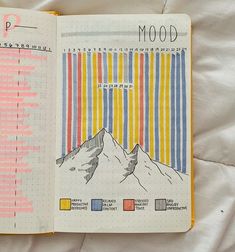 an open notebook with colorful lines and mountains in it, on top of a sheet of paper