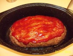 a hamburger covered in ketchup sitting on top of a pan