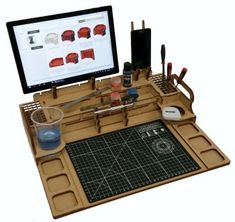 a computer monitor sitting on top of a wooden desk with tools and supplies in front of it