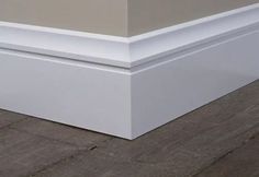 the corner of an empty room with wood flooring and white trim on the walls