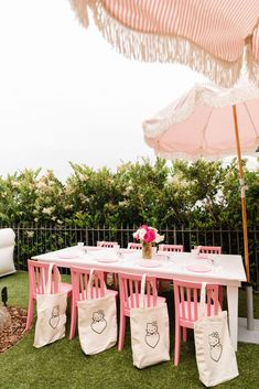 a table with pink chairs and an umbrella