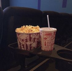 two cups of popcorn sitting on top of a black tray next to each other in front of a blue wall