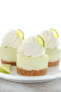 three small cheesecakes on a white plate with lime slices