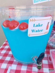 there is a blue liquid with red buttons in the water and a sign that says lake water