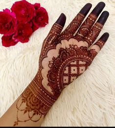 a henna on someone's hand next to some flowers