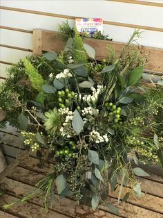 a vase filled with flowers and greenery on top of a wooden bench