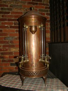 a large metal pot sitting on top of a table next to a brick wall and checkered table cloth