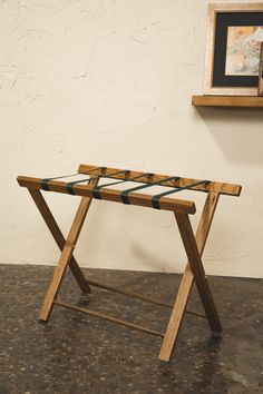 a wooden table sitting on top of a floor next to a framed picture above it