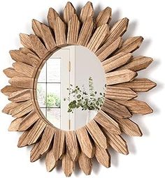 a wooden sunburst mirror hanging on the wall next to a vase with flowers in it