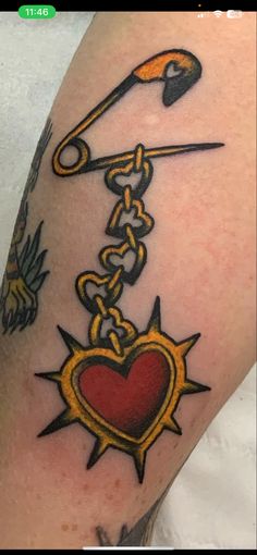 a tattoo on the arm of a person with scissors and a heart hanging from it