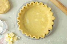 an uncooked pie crust sits on a table next to other baking supplies