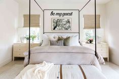 a white bedroom with four poster bed and pillows on the bottom row, along with two nightstands