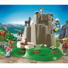 a playmobil scene with people and animals on a hill near a mountain lake