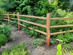 a wooden fence surrounded by green plants and trees