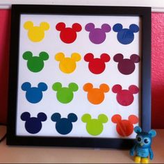 mickey mouse cut outs are displayed in front of a black frame with a blue teddy bear next to it