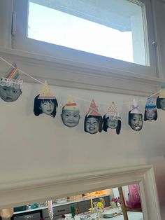 a group of children's birthday hats hanging from a line in front of a window