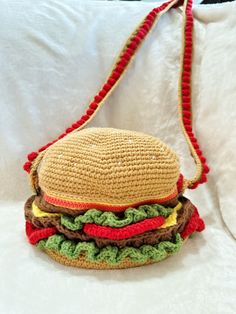 a crocheted hamburger bag sitting on top of a bed