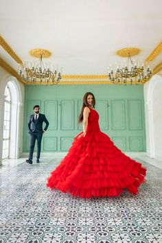 a woman in a long red dress standing next to a man in a black suit