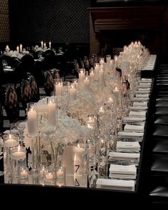 a long table is set with many candles and place settings for the guests to sit down