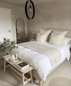 a white bed sitting in a bedroom next to a table with two candles on it