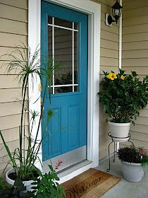 a blue front door with two potted plants on the side and a welcome mat