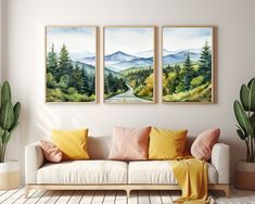 three paintings hang on the wall above a couch in a room with wooden flooring