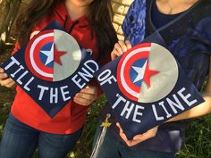 two girls holding up signs that say tell the end of the line and captain america