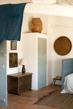 a bed room with a neatly made bed and two vases on top of the headboard