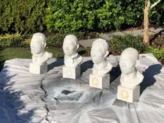 four white marble busturines sitting on top of a table