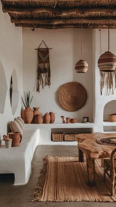 a living room filled with lots of furniture and hanging baskets on the wall next to a wooden table