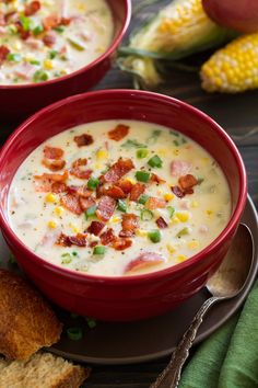 two red bowls filled with soup on top of a plate next to corn and bread